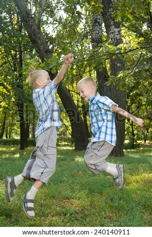 Two jumping twin brothers outdoor portrait