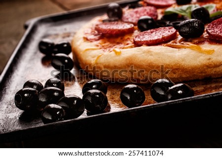 Pepperoni pizza on oven rack, shallow depth of field, focus on olives