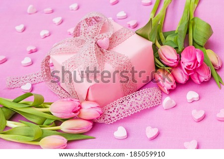 pink gift with hearts and tulips on pink background