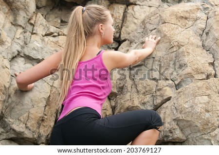 Image of blonde lady climbing on the rock. Fitness training