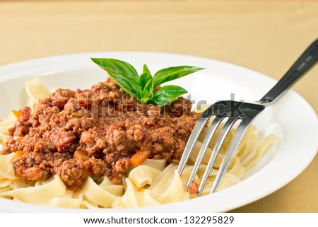 Plate of spaghetti with tomato beef sauce topped with basil