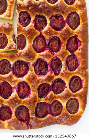 Plum cake and slices of plum cake on a baking paper. Top view