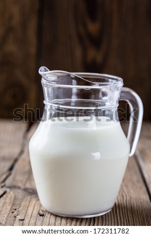 Dairy milk product. A milk jug on wooden board