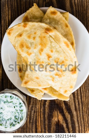 Frying pan baked flat bread on a plate with glass of sour milk. Yantyk - traditional Crimean tatar flatbread viewed from above