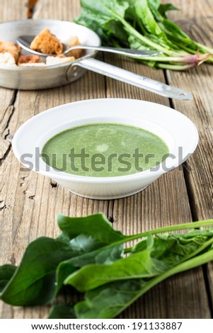 Spinach cream soup with  fresh spinach leaves and croutons on wooden background