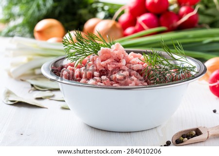 Raw ground meat in white bowl. Minced pork on a background of fresh organic vegetables