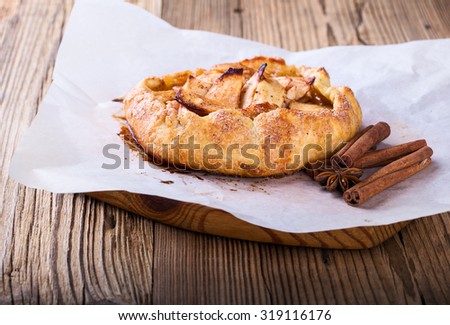 Homemade galette, crusty pie with apples on rustic wooden board