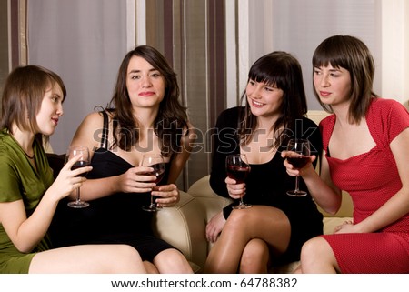 Four attractive young women in evening wear with wine