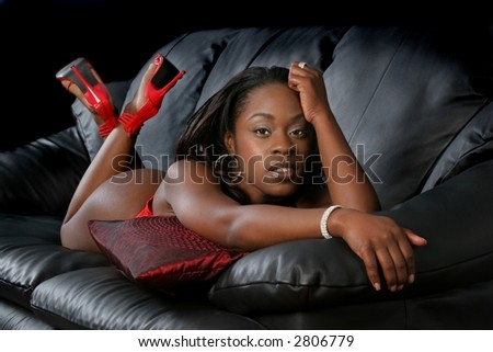Sexy black woman in lingerie and red high heels on couch