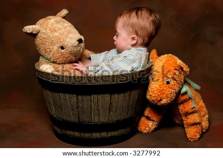 cute baby sitting in barrel with stuffed animal toys