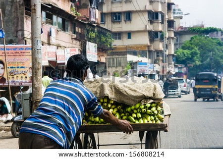 A banana seller pushes his cart thru the streets of Mumbai, India