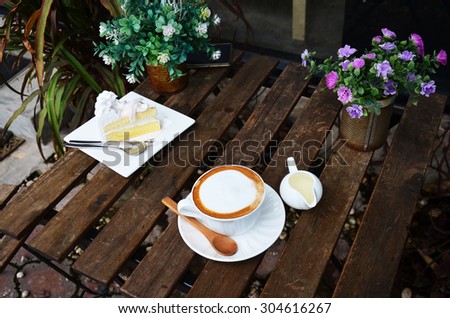 Hot Coffee and Coconut Cake on table in garden of coffee shop