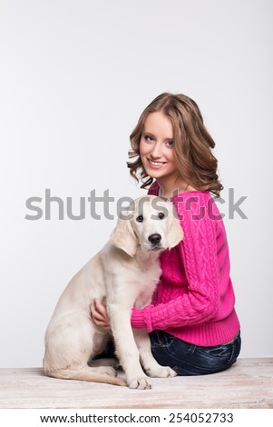 Young woman with her pet, golden retriever in studio