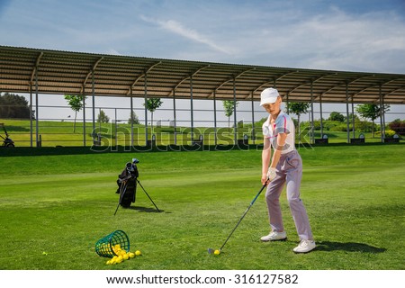 Girl golf player practicing in golf school