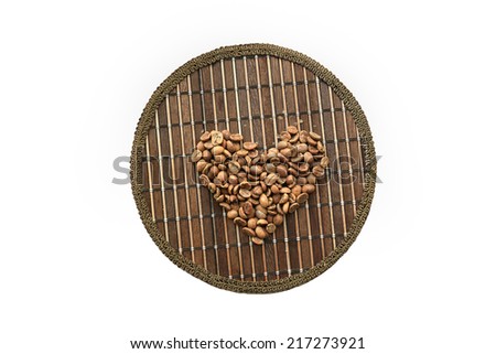 Heart of coffee beans on a round matting isolated