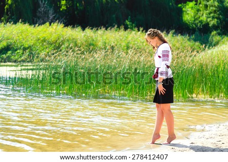 Young woman in the Ukrainian national clothes embroidery on the riverside