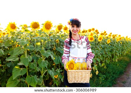 Smiling girl in embroidery holding a basket with sunflower oil