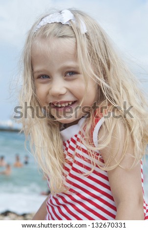 Cheerful girl with disheveled hair in the wind at the beach on a sunny day, close-up