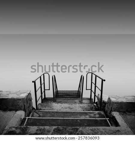 steps to nowhere. beautiful minimalist black and white seascape with stairs into the sea and milk water. shot taken in daytime with long exposure