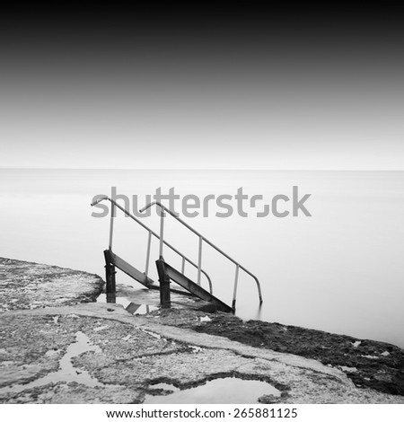 steps to nowhere. beautiful minimalist black and white seascape with stairs into the sea and milk water. shot taken in daytime
