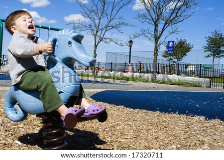 A seahorse bucks a riding toddler at the playground in landscape orientation