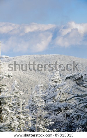 Clouds part over a snowy mountain on a cold winter day in vertical perspective