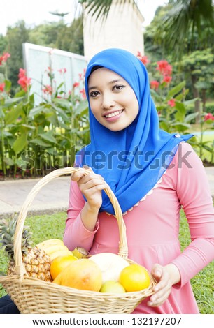 polite muslim girl holding basket with fruit