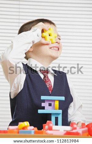 Smiling boy looking through yellow toy block