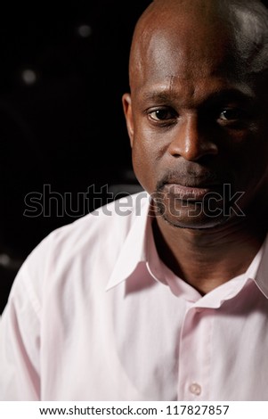Closeup portrait of african man in pink shirt looking to camera