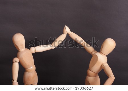 Two wooden dolls in greeting pose over dark background