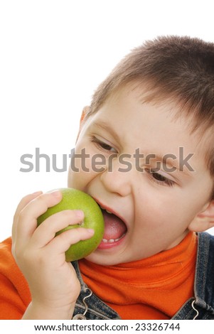 Little boy biting off green apple over white background