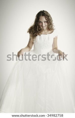 Pretty young fair-haired curly bride raising dress skirt