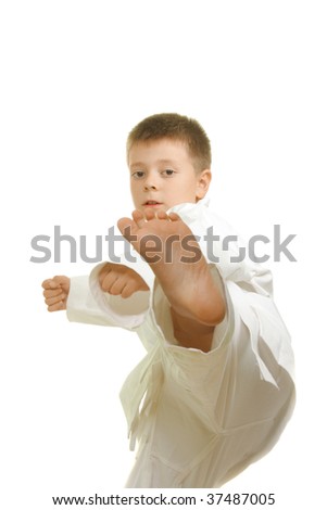 Karate boy making straight kick against white background