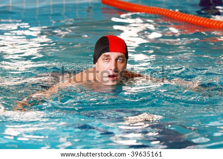 Man wearing red cap in swimming pool looks to camera
