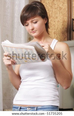 Brunette woman with reading paper against kitchen cupboard low angle view