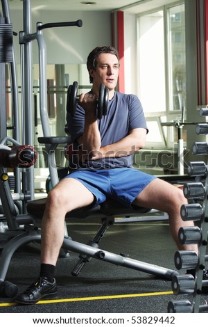 Man in shirt and shorts at gym have workout with dumb-bell