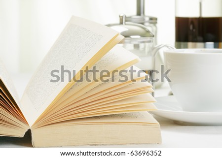 Book and coffee with various food on white tablecloth
