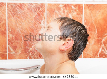 Little boy in bath enjoying water flushing from shower