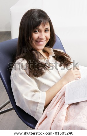 Smiling brunette woman in chair with magazine