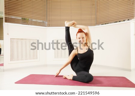 Redhead exercising yoga pose leg over head