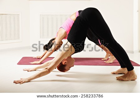 Yoga instructor shows downward facing dog pose to student