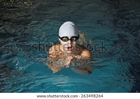 Kid in goggles swimming breaststroke in pool closeup photo