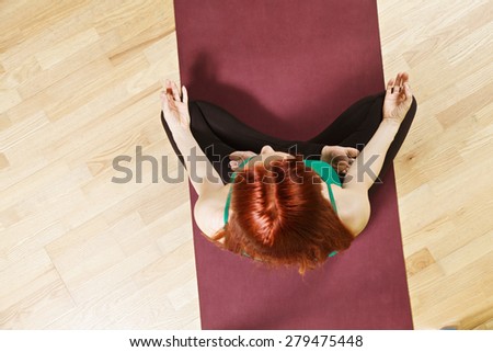 Above view at lotus yoga pose taken by caucasian redhead woman wearing green shirt