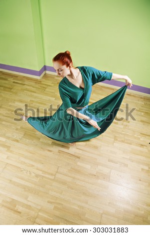 Caucasian redhead woman dancing in a green room high angle view
