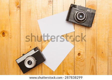 two old cameras and photos on wooden background