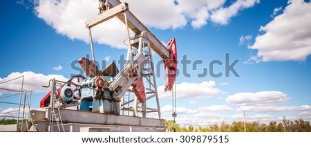 Oil pump in the open air, on a background of the cloudy sky, panorama