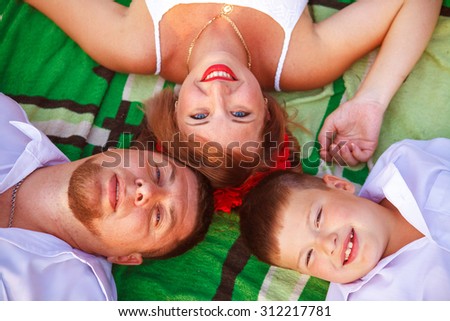 mom dad and son lie on the rug head to head top view