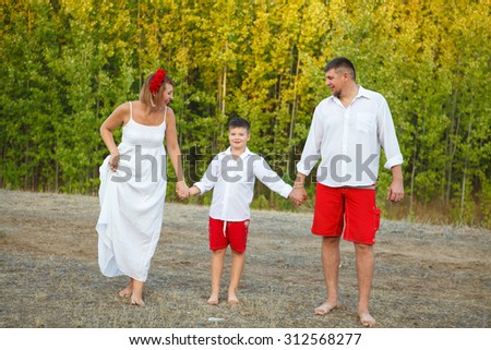 Mom Dad and son walking through the woods hand in hand