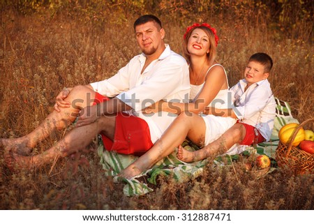 mom dad and son posing in the park sitting on the plaid outdoors