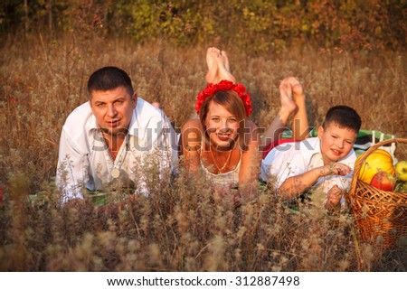 mom dad and son lie on the rug next to each other in the park outdoors